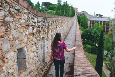 Rear view of woman standing against wall