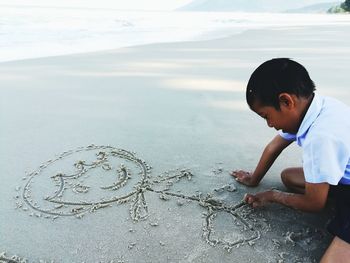 Boy drawing on sand at beach