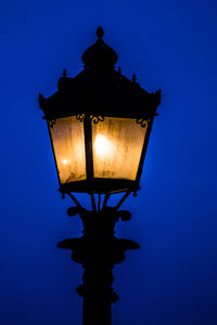 Low angle view of illuminated street light against blue sky