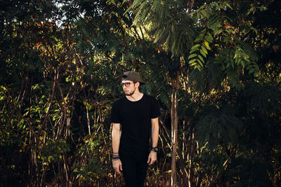 Portrait of young woman standing against trees