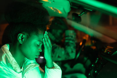 Sad african couple in quarrel sitting in car at night time, depressed african man and woman in auto