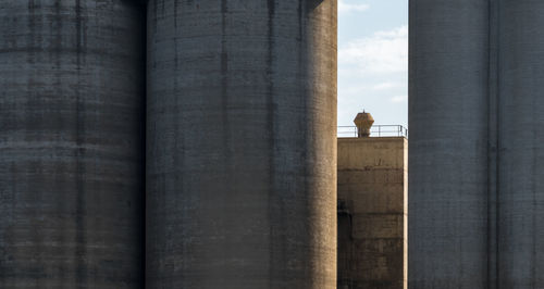 Silos made of solid concrete and a chimney standing in the sunshine