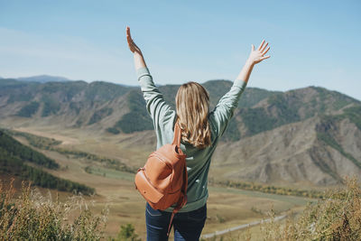 Young woman traveler in casual clothes with backpack from back on background 