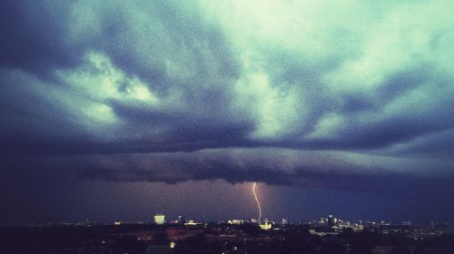 Illuminated cityscape against cloudy sky