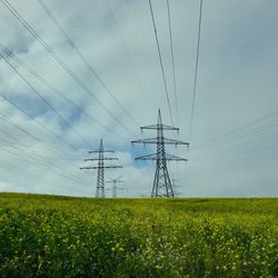 Electricity pylon 110 kv on canolafield against sky