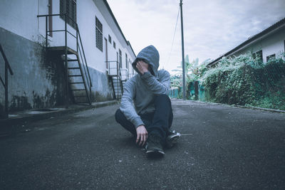 Full length of man sitting on road in city