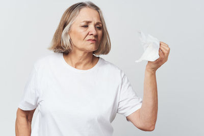 Senior woman holding tissue paper against white background