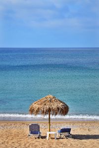 Deck chairs on beach against sky