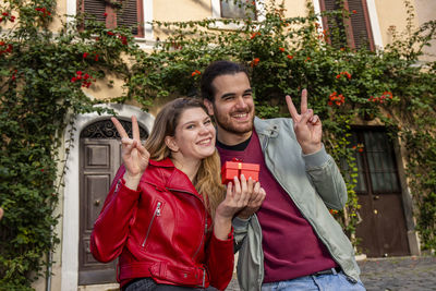 Portrait of smiling young woman using mobile phone while standing in yard