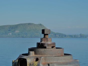 Close-up of rusty metal by sea against clear sky