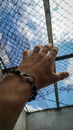 Close-up of man hand on chainlink fence