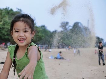 Portrait of cute girl playing with sand at beach