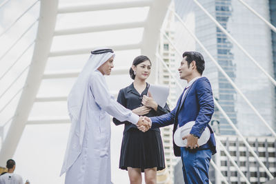 Business people handshaking against metallic structure