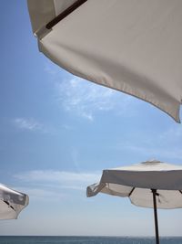 Low angle view of parasols at beach against sky during sunny day