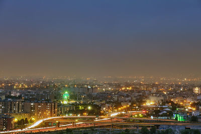 High angle view of illuminated city buildings against clear sky at night