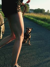 Woman with dog on field by road