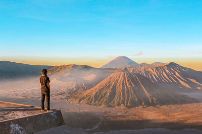 Man standing at observation point against mountains during sunset