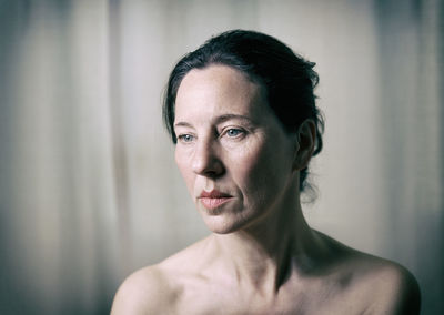 Close-up of topless mature woman looking away at home