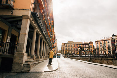 Rear view of a man walking along buildings