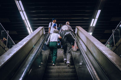 Rear view of people walking on escalator