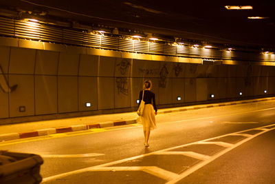 Rear view of woman walking on illuminated bus at night