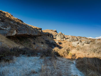 Rock formations on landscape against clear blue sky