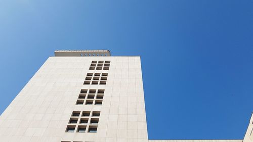 Low angle view of office building against blue sky