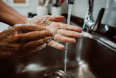 Cropped image of man washing hands in sink