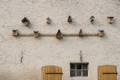 Low angle view various shape birdhouses on wall