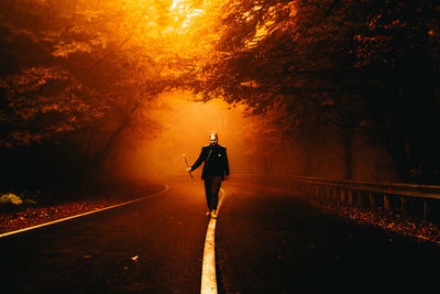 Rear view of man walking on footpath during autumn