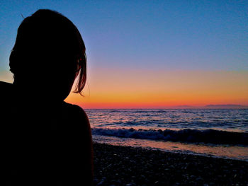Rear view of silhouette woman looking at sea during sunset