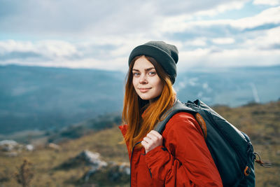 Young woman looking at camera against sky