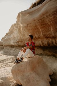 Woman sitting on rock at beach