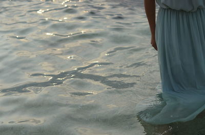 Low section of woman standing in sea 