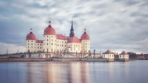 Buildings by river against sky