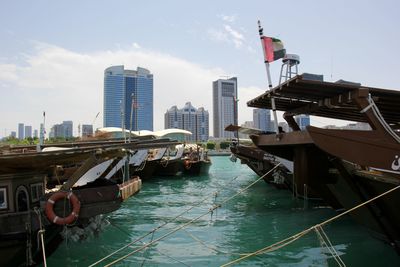 Boats moored in city against sky