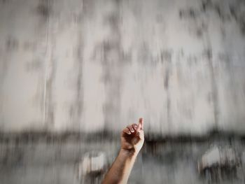 Low angle view of man hand pointing against blurred wall