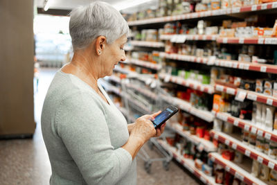 Caucasian elderly woman with white hair shopping in supermarket