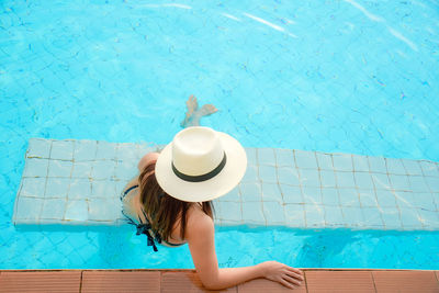 Woman sitting by swimming pool