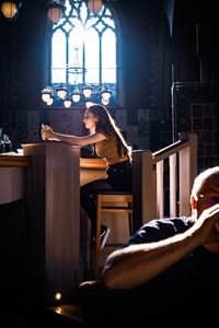 Side view of woman sitting on table at church