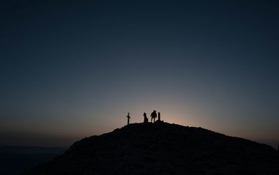 Silhouette man standing on rock against sky during sunset