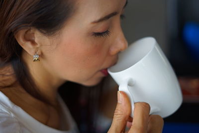 Close-up of woman drinking coffee at home