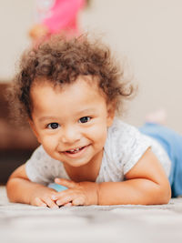 Portrait of cute mixed race baby  boy with curly hair smiling and looking at the cameras 