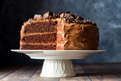 A delicious homemade triple layered low sugar chocolate cake on a pedestal stand