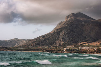 Scenic view of sea and mountains against sky crashing waves cloud