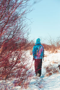 Rear view of woman with backpack walking on snow covered landscape
