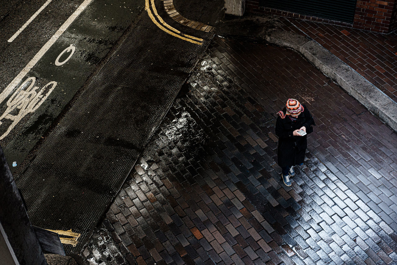 HIGH ANGLE VIEW OF WOMAN STANDING ON CITY