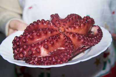 Woman holding plate with cooked octopus