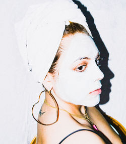 Close-up portrait of young woman against white wall