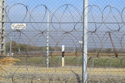 Chainlink fence on field against sky